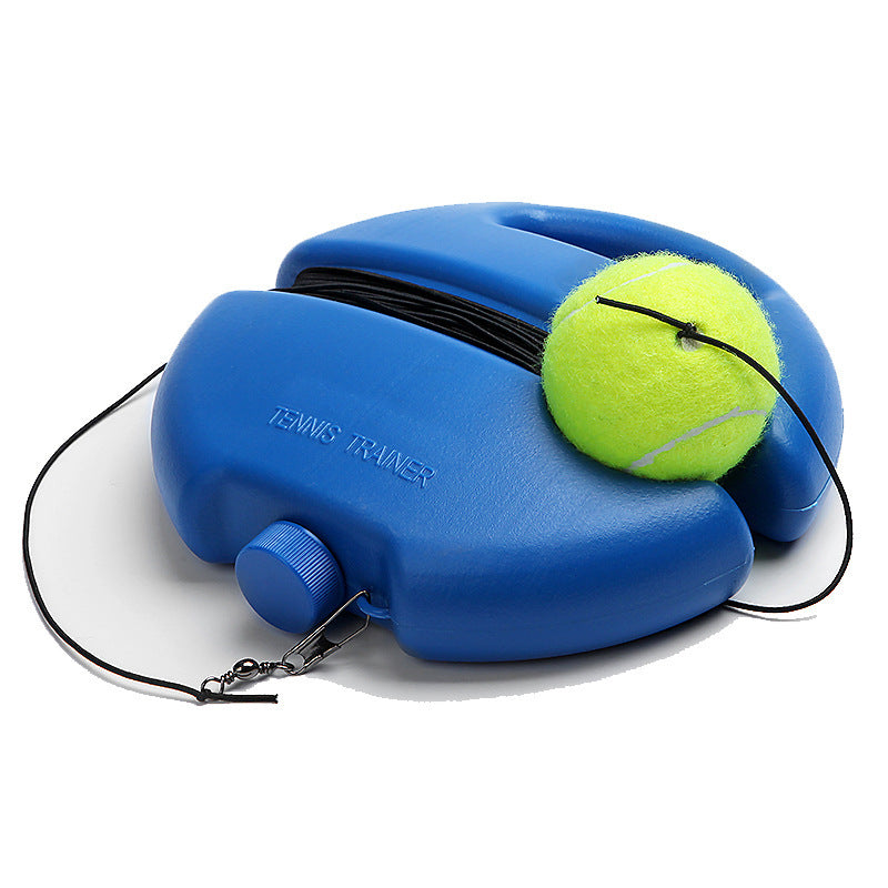 A blue tennis ball retriever tool with a handle, black elastic band, and a yellow tennis ball resting on top, photographed on a light gray studio background.