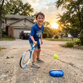 Child practicing tennis in a driveway with the solo trainer